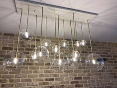 a chandelier hanging from the ceiling in front of a brick wall with lights on it