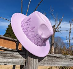 This truly one of a kind small brim fedora is perfect to add a stylish flare to your outfit or hang as a unique floral wall decoration. It's burned entirely by hand using a pyrography tool with an original and completely free-handed design (never using a stencil or laser machine.) This design features lavender flowers growing up along the entire hat's crown.  Size Medium has 56-58cm crown while Size Large has a 59-62cm crown but fits most with an adjustable tie band inside Hat has a roughly 2.5 Short Brim Felt Hat For Country Events In Spring, Spring Country Events Felt Hat With Short Brim, Spring Felt Hat With Short Brim For Country Events, Whimsical Short Brim Fedora For Summer, Whimsical Summer Fedora With Short Brim, Adjustable Felt Bucket Hat For Spring, Adjustable Flat Brim Top Hat For Garden Party, Whimsical Short Brim Fedora For Kentucky Derby, Adjustable Short Brim Fedora For Garden Party