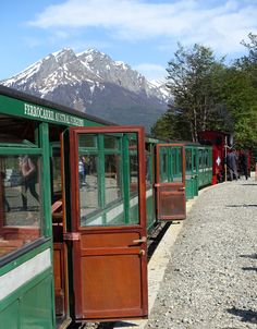 an old fashioned train is parked on the tracks with mountains in the backgroud