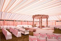 the inside of a tent decorated with pink and white linens for a wedding ceremony