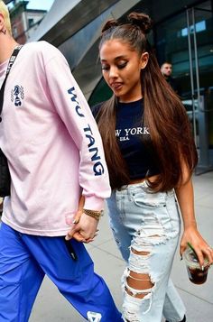 a man and woman walking down the street with their hands in each other's pockets