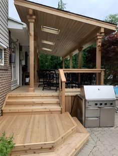 an outdoor kitchen and grill area with wooden steps leading up to the back deck,