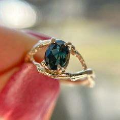 a close up of a person holding a ring with a blue stone in the middle