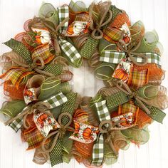 a wreath made out of mesh and fabric with pumpkins on the front, sitting on a white door