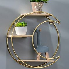 a gold circular shelf with two plants and a giraffe figurine on it