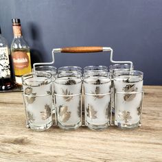 six shot glasses are lined up on a table next to bottles and a corkscrew