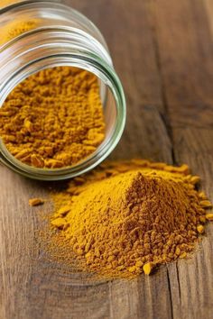 two jars filled with yellow powder on top of a wooden table