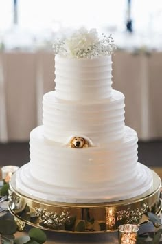 a three tiered white wedding cake on top of a gold platter with flowers