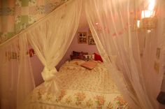 a canopy bed with white curtains and pink pillows