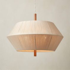 a white lamp hanging from a ceiling with a wooden stick sticking out of it's center