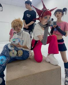 three people sitting on top of a cardboard box with head phones in their ears and one holding a camera