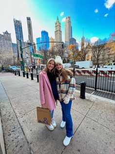 two women standing on the sidewalk in front of a city skyline