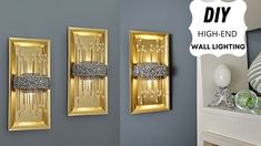 two gold wall lights are hanging on the wall next to a mirror and vases