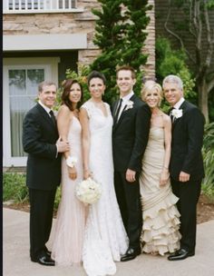 a group of people standing next to each other in front of a building and trees