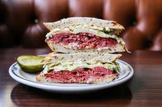 a sandwich cut in half sitting on top of a plate next to a pickle