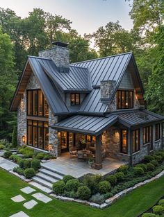 a house with stone and metal roofing in the middle of a lush green yard