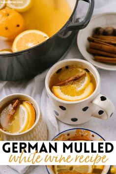 the german mulled white wine recipe is served in two mugs with orange slices and cinnamon sticks