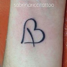 a small heart tattoo on the wrist with a black outline in the shape of a heart