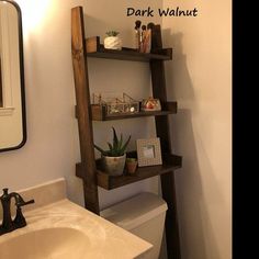 a bathroom with a toilet, sink and wooden ladder shelving unit in the corner