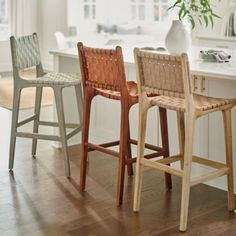 three wooden stools sitting in front of a white counter top next to a window