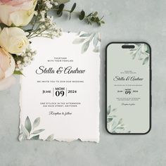 an elegant wedding card with flowers on the table next to it and a cell phone