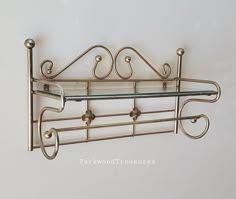 there is a metal shelf with glass shelves on the top and two hooks attached to it