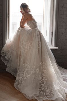 a woman in a wedding dress leaning against a window