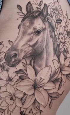 a woman's stomach with a horse and flowers tattoo on the side of her thigh