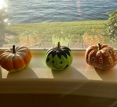 three painted pumpkins sitting on a window sill