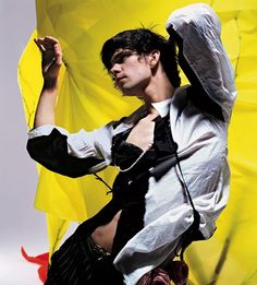 a man in white shirt and tie standing next to yellow umbrella with his hands up