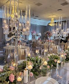 a table with candles and flowers on it in a room filled with tables cloths