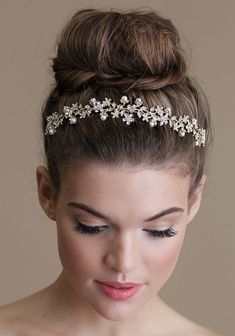 a woman wearing a bridal headpiece with flowers and pearls on the top of her hair