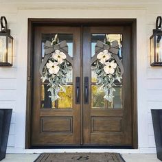 the front door is decorated with two wreaths and flowers on it's side