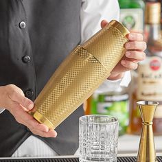 a bartender is holding a gold shaker in his hand