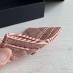 a hand holding a pink wallet on top of a table