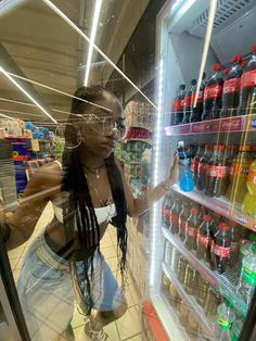 a woman standing in front of a refrigerator filled with drinks