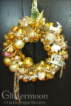 a gold christmas wreath with ornaments hanging on it's front door for the holiday season