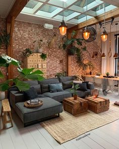 a living room filled with lots of furniture and plants on the wall above it's windows