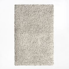 an area rug with white and gray colors on the floor in front of a white wall