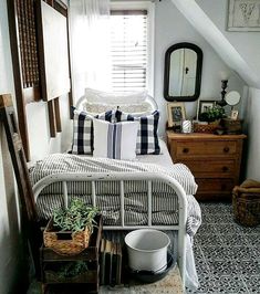 a white bed sitting under a window in a bedroom next to a dresser and mirror