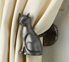 a silver cat figurine sitting on top of a curtain