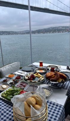 a table full of food on the deck of a boat in front of a bridge