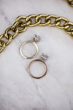 two rings and a chain on a white marble counter top, with one diamond in the middle