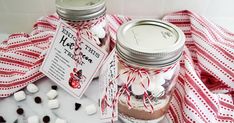 two mason jars filled with marshmallows on top of a red and white table cloth