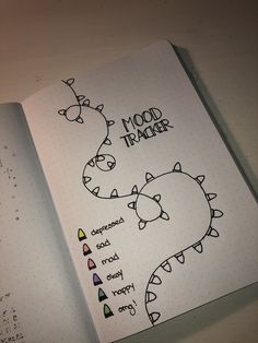 an open notebook with drawings on it and the words mood tracker written in cursive writing