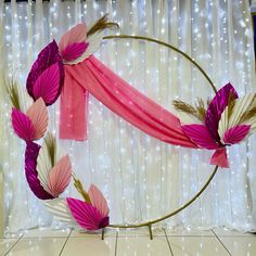 an artistic display with pink and white paper flowers on a gold circle, surrounded by string lights