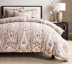 a bed with a brown and white comforter on top of it next to a night stand