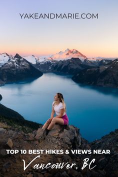 a woman sitting on top of a mountain next to a lake