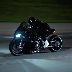 a man riding on the back of a motorcycle at night