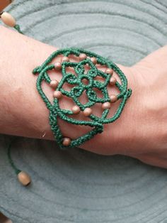 I have made this bracelet in grass green combined with a toasted beige color present in the wooden beads that adorn the bracelet. It is a bracelet with a mandala design and boho style, very light and attractive. The closure is sliding, so the bracelet can be adjusted to the desired size. I have finished it with two raw-colored wooden beads that hang from the ends of the chain. The width of the widest part of the bracelet is 5 cm (1.96 in) approx. The maximum length of the chain is approximately Earthy Macrame Bracelets As Gift, Green Macrame Beaded Bracelets For Festivals, Earthy Macrame Braided Bracelet Gift, Bohemian Green Braided Bracelets For Festivals, Green Macrame Bohemian Bracelets, Green Bohemian Macrame Bracelets, Green Bohemian Bracelets With Adjustable Cord, Green Macrame Braided Bracelets For Festival, Green Macrame Braided Bracelet For Festival